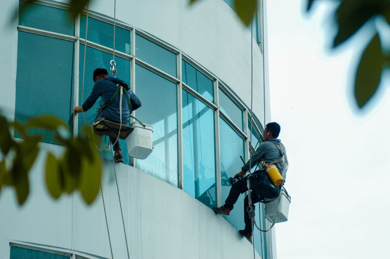 gallery-6 Window cleaners suspended on ropes clean a high-rise buildings glass exterior.